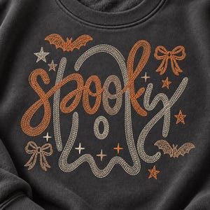 以下が含まれることがあります： チャコールグレーのクルーネックトレーナーで、「spooky」という文字が筆記体で刺繍されています。グラフィックには、中央のゴーストの輪郭、2匹のコウモリ、2つのリボン、そしてオレンジとクリーム色の糸で縫い取られたいくつかの小さな星がデザインされています。