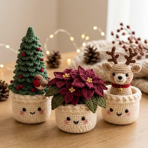 May include: Three crocheted amigurumi figures in cream-colored pots with smiling faces and pink cheeks. The left pot holds a green Christmas tree with red berries and a small bird. The center pot holds a red poinsettia. The right pot holds a reindeer.