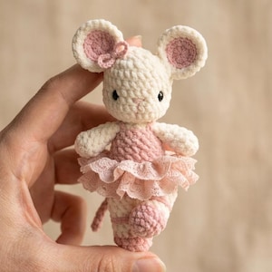 Può includere: Una piccola statuetta di topo all'uncinetto in filato color crema, con orecchie interne rosa e un corpetto in filato rosa. Il topo indossa una gonna in pizzo rosa a balze sovrapposte e scarpette da ballo in filato rosa abbinate ai piedi.