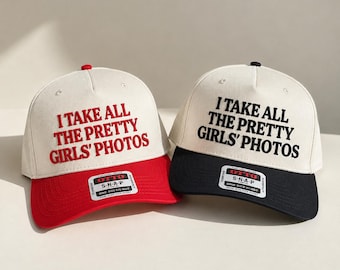 May include: Two snapback caps with off-white crowns and colored brims. The left cap has a red brim and red embroidered text reading I TAKE ALL THE PRETTY GIRLS' PHOTOS. The right cap has a black brim and black embroidered text reading the same.