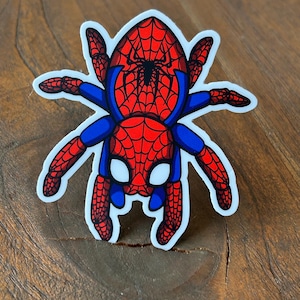 May include: A sticker featuring a cartoon spider with a red and blue costume. The spider has a red web pattern on its body and blue arms and legs. The spider's eyes are white, and a black spider emblem is on its chest.