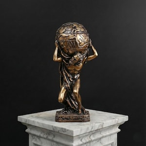 Puede incluir: Estatua de color bronce de Atlas sosteniendo un globo. La estatua presenta diseños intrincados y se encuentra sobre un pedestal de mármol. El fondo es negro liso.