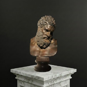 Puede incluir: Busto de bronce de un hombre con barba espesa y cabello rizado, montado sobre una base de madera oscura. El busto se exhibe sobre un pedestal de mármol blanco sobre un fondo oscuro. La escultura tiene una estética clásica.