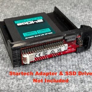 May include: A black Startech adapter with a red circuit board and a black SSD drive. The SSD drive is labelled "240GB" and "SOLID STATE DRIVE". The text "Startech Adapter & SSD Drive Not Included" is visible.