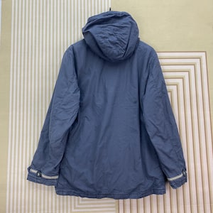 May include: A blue hooded jacket with a full zipper closure. The jacket has a drawstring hood, long sleeves, and a straight hemline. The cuffs have a white and yellow stripe detail. The jacket is made of a lightweight material.