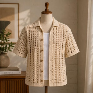 May include: A beige, open-weave crochet shirt with short sleeves and a collared neckline. The shirt is buttoned up and worn over a white tank top. The shirt is displayed on a mannequin.