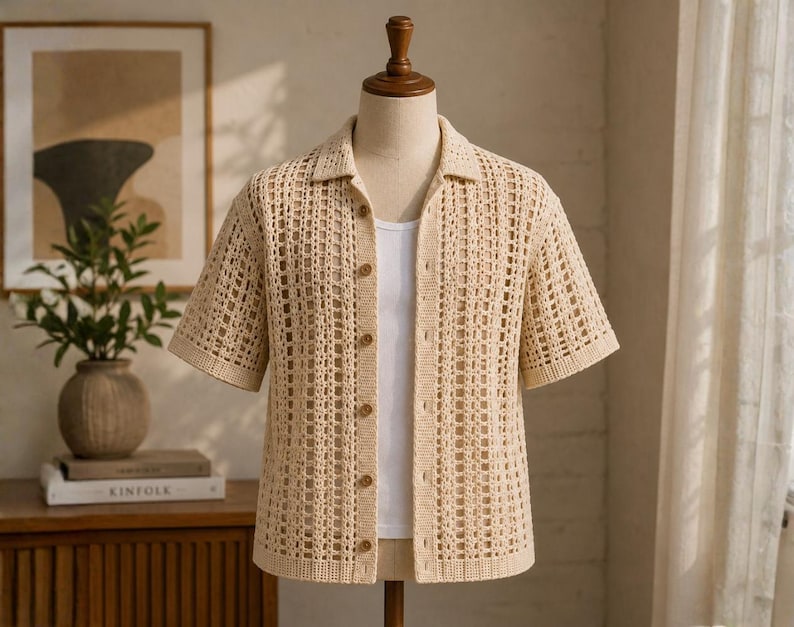 May include: A beige, open-weave crochet shirt with short sleeves and a collared neckline. The shirt is buttoned up and worn over a white tank top. The shirt is displayed on a mannequin.