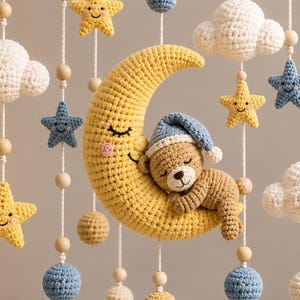 May include: A handmade crochet baby mobile featuring a yellow crescent moon with a sleeping teddy bear wearing a blue cap. The mobile includes yellow stars, white clouds, blue stars, and wooden beads, all suspended by white string.