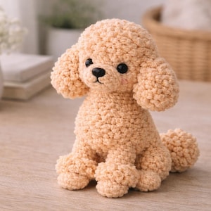 Puede incluir: Un juguete de peluche con forma de perro caniche de color marrón claro, con ojos y nariz negros. El animal de peluche hecho a mano tiene un aspecto texturizado y rizado y está sentado erguido. El juguete está sobre una superficie de madera clara.