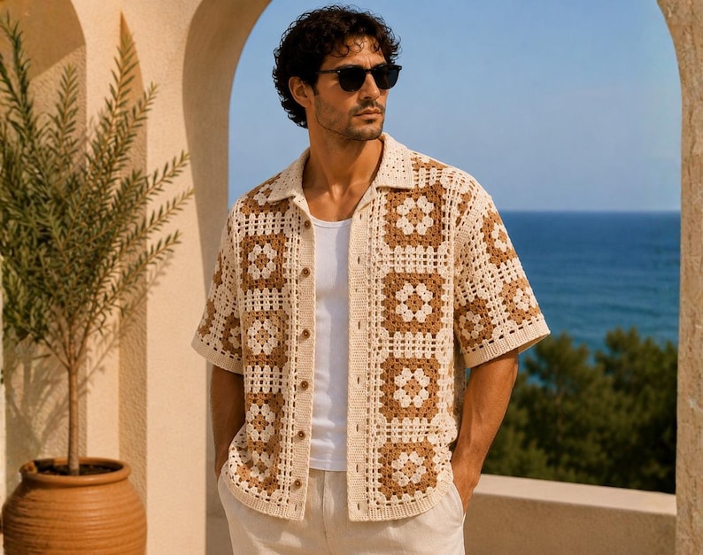 K&ouml;nnte beinhalten: Ein kurz&auml;rmeliges H&auml;kelhemd in Creme und Braun mit Knopfleiste. Das Hemd hat ein quadratisches Muster und einen Kragen. Die Person auf dem Bild tr&auml;gt eine Sonnenbrille und ein wei&szlig;es Unterhemd. Der Hintergrund zeigt das Meer und eine Topfpflanze.
