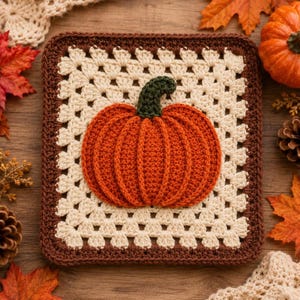 May include: A square crochet granny square featuring a central three-dimensional orange pumpkin with a dark green stem. The pumpkin is centered on a cream-colored background with a dark brown border, crafted with intricate yarn stitching throughout.