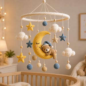 May include: A handcrafted baby mobile with a yellow crescent moon holding a sleeping teddy bear, alongside crocheted stars, clouds, and spheres in yellow, blue, and white. The mobile hangs from a circular frame.