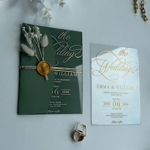 Puede incluir: Conjunto de invitaciones de boda con una tarjeta verde con letras doradas y un sello de cera, y una tarjeta acrílica transparente con letras doradas. La tarjeta verde incluye los nombres "WILLIAM" y la fecha "16 2026". También hay un anillo de bodas de oro.