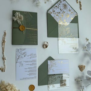 Può includere: Invito di nozze verde oliva con dettagli floreali dorati. Include biglietti d'invito, buste e biglietti di RSVP. Presenta un sigillo di cera e delicate decorazioni floreali. La suite è disposta con gioielli e accenti floreali.