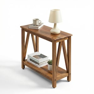 May include: A wooden side table with a lower shelf and angled legs. A small lamp with a cream-colored shade sits on top, along with a mug and books. A small potted plant is on the lower shelf. The table is made of a warm-toned wood.