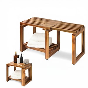 May include: Wooden bathroom bench with a slatted top and a lower shelf. The bench is a warm brown color and holds folded white towels. A smaller matching side table with towels and toiletries is also shown.