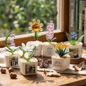 May include: Six small white square ceramic pots containing glass flowers. The pots feature printed photos, text including Happy Father's Day and Merry Christmas, and green glass stems. The flowers are yellow, pink, white, purple, and blue.