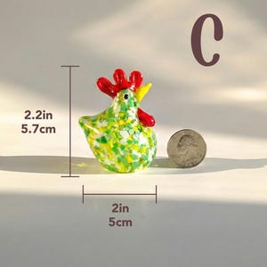 May include: A colorful glass rooster figurine, 2.2 inches tall and 2 inches wide, with red comb and wattle, yellow beak, and a body speckled with green and yellow. The figurine weighs 85g.