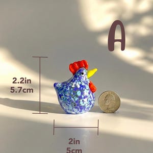 May include: A small, decorative glass rooster figurine. The rooster is blue with white and blue floral patterns, a red comb, and a yellow beak. It measures 2 inches wide, 2.2 inches tall, and weighs 85g.