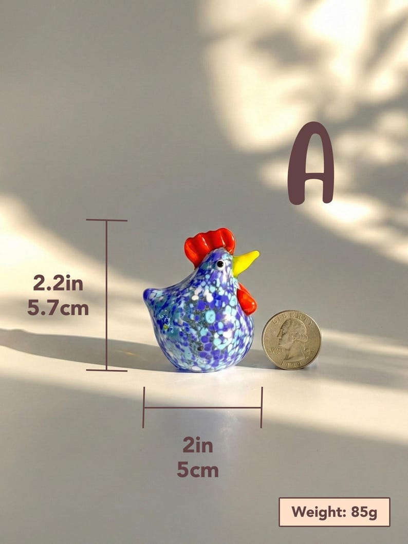 May include: A small, decorative glass rooster figurine. The rooster is blue with white and blue floral patterns, a red comb, and a yellow beak. It measures 2 inches wide, 2.2 inches tall, and weighs 85g.