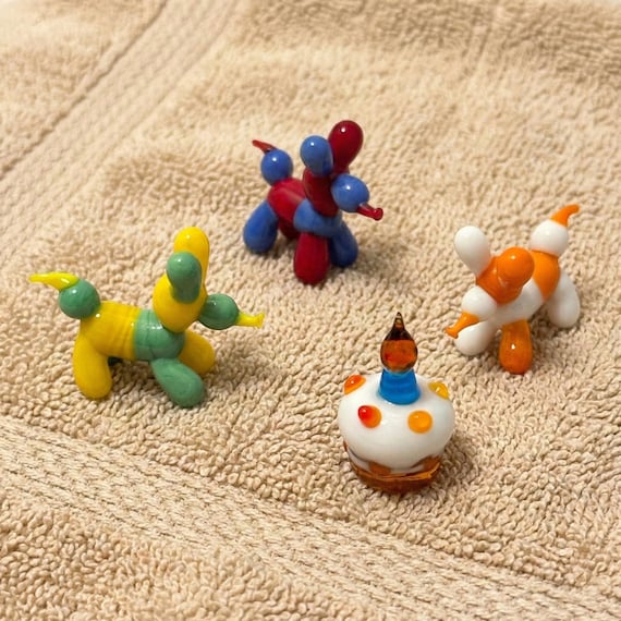 A lampwork glass balloon dog — Jeff Koons energy, but tiny, handmade, and on your desk for $30.