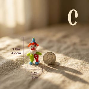 May include: A miniature glass clown figurine, 1.8 inches tall and 1.2 inches wide, with a red, white, blue, and green color scheme. The clown has a smiling face and is next to a quarter for size comparison. The letter "C" is in the background.