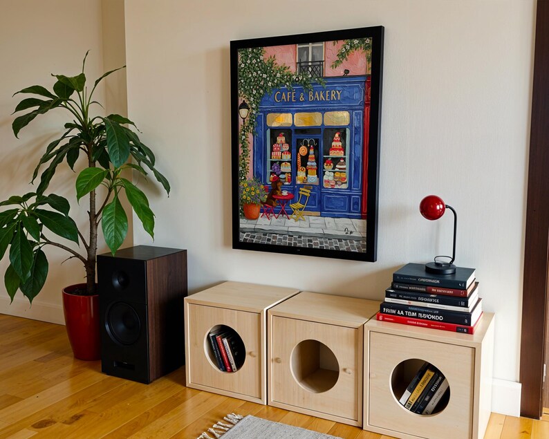 Charming Paris café art print featuring a classic blue storefront on a quaint city street, with a small dog waiting patiently beside a table of pastries. Croissants and coffee add a cozy morning feel, while soft light and European details evoke a relaxed Parisian atmosphere. Elegant yet whimsical wall art perfect for kitchens, cafés, or living spaces, celebrating travel, food, and everyday moments in France.