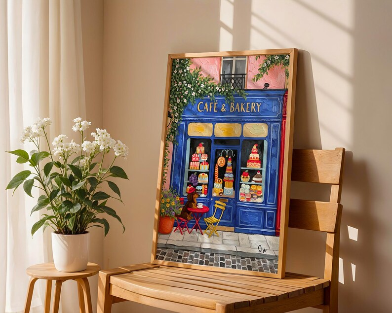 Charming Paris café art print featuring a classic blue storefront on a quaint city street, with a small dog waiting patiently beside a table of pastries. Croissants and coffee add a cozy morning feel, while soft light and European details evoke a relaxed Parisian atmosphere. Elegant yet whimsical wall art perfect for kitchens, cafés, or living spaces, celebrating travel, food, and everyday moments in France.