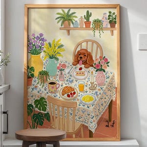 Op de afbeelding: Een ingelijste kunstdruk toont een ontbijtscene met een Cavalier King Charles Spaniel. De tafel is gedekt met een bloemig tafelkleed, eten en bloemen. Een houten plank erboven toont potplanten. Het kunstwerk zit in een houten lijst.