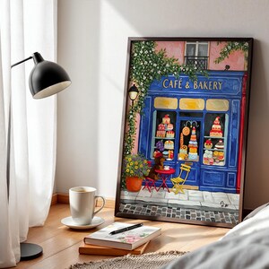 Charming Paris café art print featuring a classic blue storefront on a quaint city street, with a small dog waiting patiently beside a table of pastries. Croissants and coffee add a cozy morning feel, while soft light and European details evoke a relaxed Parisian atmosphere. Elegant yet whimsical wall art perfect for kitchens, cafés, or living spaces, celebrating travel, food, and everyday moments in France.