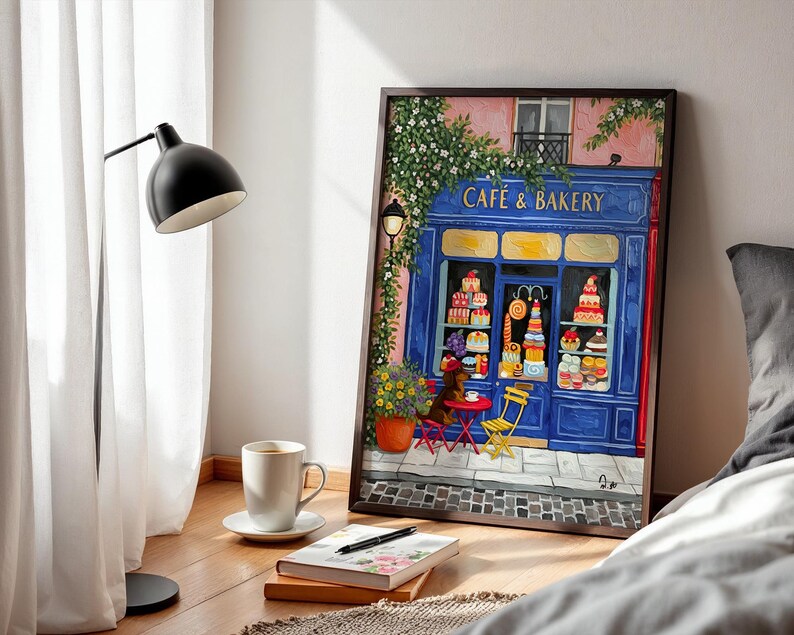 Charming Paris café art print featuring a classic blue storefront on a quaint city street, with a small dog waiting patiently beside a table of pastries. Croissants and coffee add a cozy morning feel, while soft light and European details evoke a relaxed Parisian atmosphere. Elegant yet whimsical wall art perfect for kitchens, cafés, or living spaces, celebrating travel, food, and everyday moments in France.