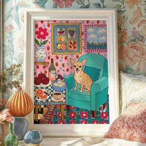 May include: A framed art print featuring a tan Chihuahua sitting in a teal armchair. The artwork includes a table with fruit, a bottle of wine, and a blue and white vase with a red flower. The background has a pink strawberry pattern.