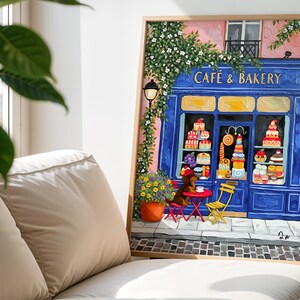 Charming Paris café art print featuring a classic blue storefront on a quaint city street, with a small dog waiting patiently beside a table of pastries. Croissants and coffee add a cozy morning feel, while soft light and European details evoke a relaxed Parisian atmosphere. Elegant yet whimsical wall art perfect for kitchens, cafés, or living spaces, celebrating travel, food, and everyday moments in France.