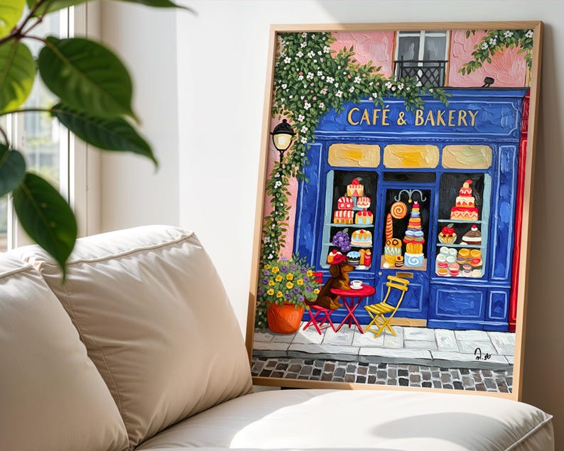 Charming Paris café art print featuring a classic blue storefront on a quaint city street, with a small dog waiting patiently beside a table of pastries. Croissants and coffee add a cozy morning feel, while soft light and European details evoke a relaxed Parisian atmosphere. Elegant yet whimsical wall art perfect for kitchens, cafés, or living spaces, celebrating travel, food, and everyday moments in France.