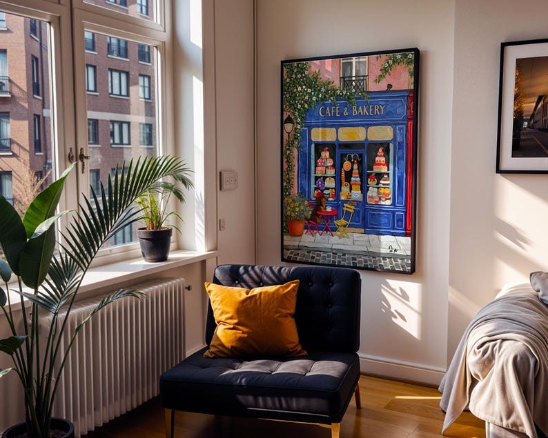 Charming Paris café art print featuring a classic blue storefront on a quaint city street, with a small dog waiting patiently beside a table of pastries. Croissants and coffee add a cozy morning feel, while soft light and European details evoke a relaxed Parisian atmosphere. Elegant yet whimsical wall art perfect for kitchens, cafés, or living spaces, celebrating travel, food, and everyday moments in France.