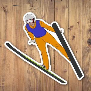 May include: A sticker featuring a cartoon illustration of a ski jumper in mid-air. The skier wears an orange jumpsuit, a blue vest, and a silver helmet with red goggles. The skis are black with a green stripe. The background is a wood grain pattern.
