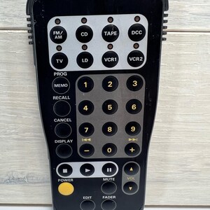 May include: A white ceramic mug with a black handle and the text "But First, Coffee" in a black, handwritten-style font. The mug is on a white surface.