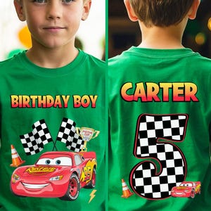 May include: Green t-shirt with the text "BIRTHDAY BOY" and a graphic of the character Lightning McQueen from the movie Cars. The shirt also features checkered flags, a trophy, and the number 95. The back of the shirt says "CARTER" and the number 5.