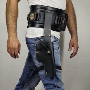 May include: Black leather holster and belt set. The holster is attached to the thigh with a strap and gold-colored rivets. The belt has multiple cartridge holders and a gold-colored emblem.