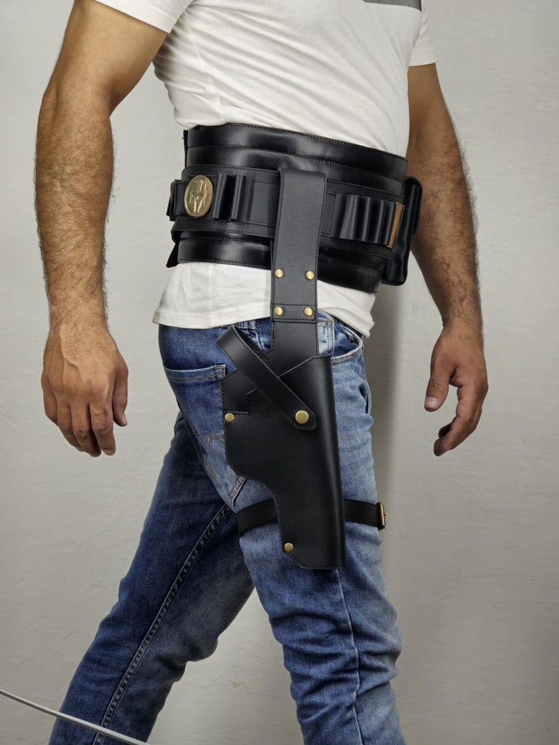 May include: Black leather holster and belt set. The holster is attached to the thigh with a strap and gold-colored rivets. The belt has multiple cartridge holders and a gold-colored emblem.
