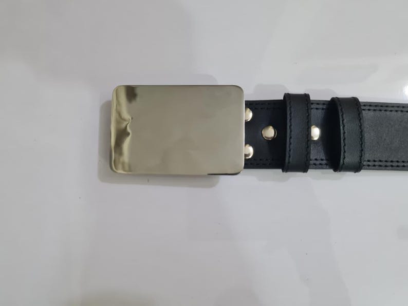 K&ouml;nnte beinhalten: Schwarzer Lederg&uuml;rtel mit einer rechteckigen, silberfarbenen Schnalle. Der G&uuml;rtel hat zwei Schlaufen und ist mit silbernen Nieten befestigt. Die N&auml;hte sind an den Kanten sichtbar und verleihen dem Design Details. Der G&uuml;rtel ist ca. 3,8 cm breit.