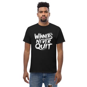 May include: Black t-shirt with the white text "WINNERS NEVER QUIT" in a bold, brushstroke style. The shirt is a classic crew neck style and is made of a soft material.