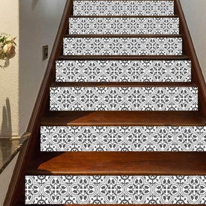 Könnte beinhalten: Ein Set aus sieben rechteckigen Treppenstufenaufklebern mit einem sich wiederholenden schwarz-weißen Blumenmuster. Jeder Aufkleber ist auf der vertikalen Fläche einer Holztreppenstufe angebracht und erzeugt ein durchgehendes Design.
