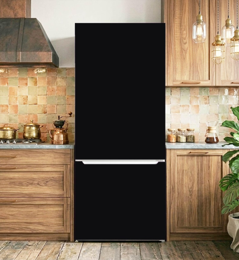K&ouml;nnte beinhalten: Ein hoher, mattschwarzer K&uuml;hlschrank mit schlichtem Design, einem unteren Gefrierfach und einem horizontalen silbernen Griff, der sich &uuml;ber die gesamte Breite der T&uuml;r erstreckt und als freistehendes Ger&auml;t in einer K&uuml;che steht.