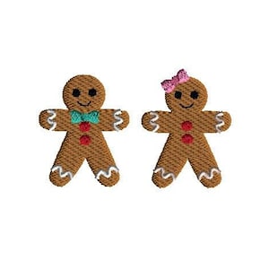 Puede incluir: Dos personas de jengibre, una con una corbata de lazo azul y la otra con un lazo rosa, están sonriendo. Ambos son marrones con glaseado blanco y botones rojos.