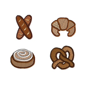 Op de afbeelding: Vier geborduurde patches met verschillende gebakken goederen: een paar gekruiste baguettes, een croissant, een kaneelrol en een pretzel.