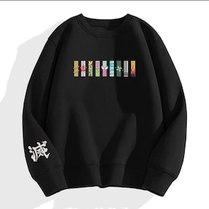 May include: Black sweatshirt with colorful graphic bars across the chest. The bars feature various designs in shades of yellow, pink, green, and blue. White Japanese characters are on the left sleeve. A casual, comfortable garment.