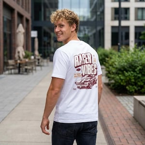 May include: White t-shirt with a maroon graphic on the back that says "Racer Vibes" with a classic car illustration. The shirt is being worn by a person in a city setting.