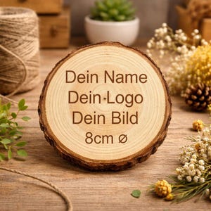 Könnte beinhalten: Ein runder Holzscheibe mit einem Durchmesser von 8 cm, graviert mit dem Text "Dein Name Dein Logo Dein Bild". Das Holz hat eine helle, braune Farbe mit sichtbaren Maserungen. Im Hintergrund befinden sich Schnur, Grün und Trockenblumen.