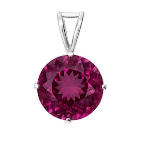May include: A round, faceted, deep magenta gemstone pendant with a silver bail. The gemstone is set in a silver setting with four prongs. The pendant is a striking piece of jewelry.